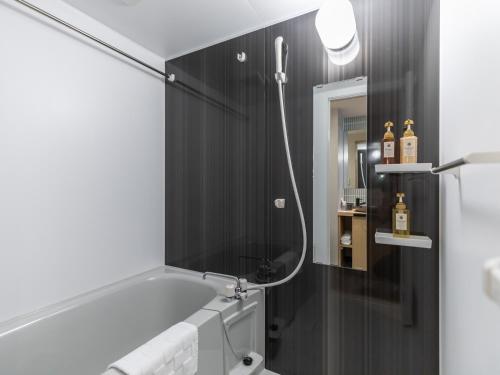 a bathroom with a bath tub and a mirror at Tabist GROOVE KYOTO OKOSHIYASU in Kyoto