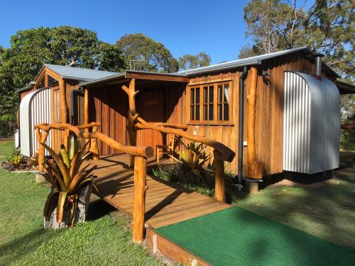 a wooden cabin with a porch and a wooden deck at MANGO LODGE River Heads in River Heads