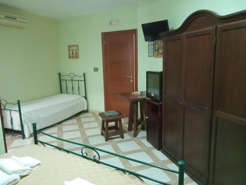 a bedroom with a bed and a tv and a cabinet at Mamma Assunta in Melendugno
