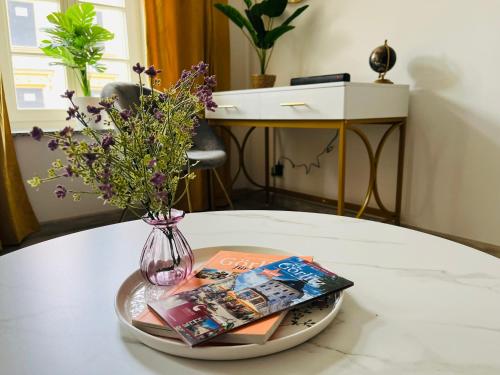 a table with a vase of flowers and magazines at FILMAP-Charmant-Modern-Zentral-Balkon-Beamer-Spieletisch in Görlitz