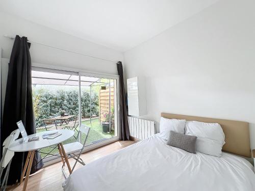 a bedroom with a bed and a table and a window at Appart'hôtel Le Clos Lassagne à Brignais - Lyon Sud in Brignais