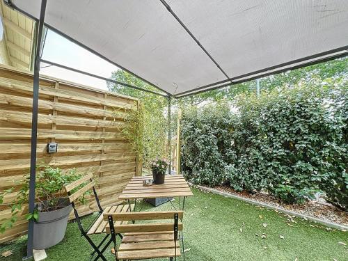a patio with a wooden table and chairs under a canopy at Appart'hôtel Le Clos Lassagne à Brignais - Lyon Sud in Brignais