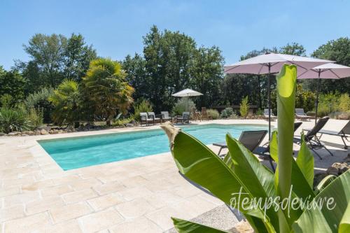 - une piscine avec un parasol et des chaises dans l'établissement Cottage O' Temps de Vivre, à Groléjac