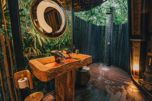 a bathroom with a stone sink and a shower at Hideout Eco Bamboo House Bali in Selat