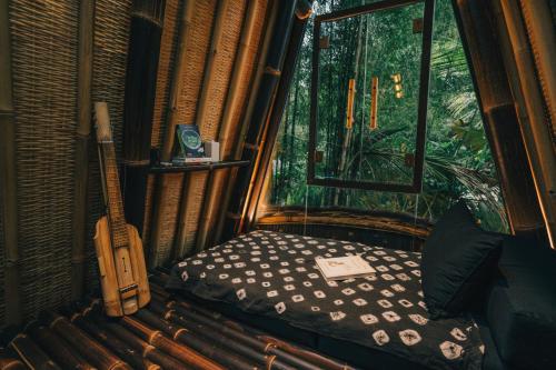 a bedroom with a bed and a guitar in a room at Hideout Eco Bamboo House Bali in Selat