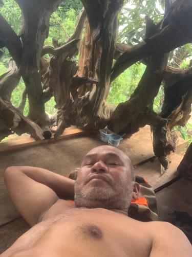 a man laying on the ground under a tree at Khu Du Lịch Sinh Thái, Nghỉ dưỡng Homestay Hoàng Ánh - Kon Xom Luh in Kon Tum