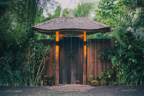 a wooden door with a gate in a forest at Hideout Eco Bamboo House Bali in Selat