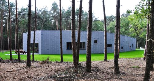 a white building in the middle of a forest at Twinstone Lodge in Genk