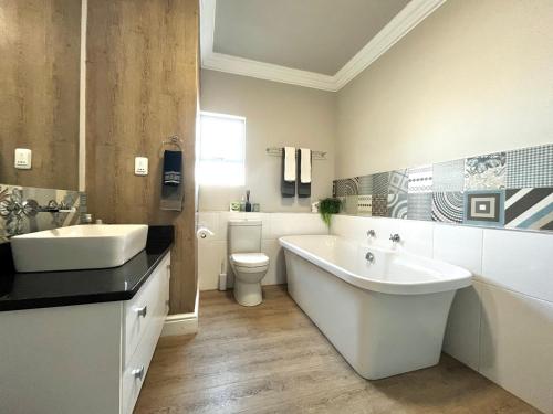 a bathroom with a tub and a sink and a toilet at Coastal Hospitality - Beach Club 401 in Mossel Bay