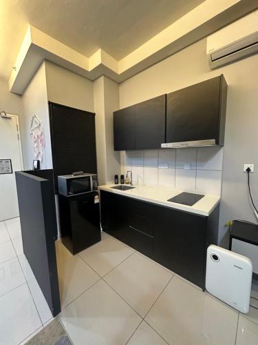 eine Küche mit schwarzen Schränken und weißem Boden in der Unterkunft Infinity Pool Netflix 100Mbps apartment in Shah Alam