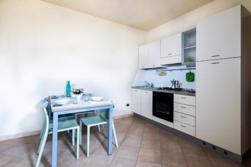 a kitchen with white cabinets and a table and chairs at Residence I Mirti in Porto Pozzo