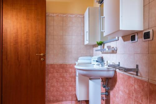 a bathroom with a white sink and a wooden door at Residence I Mirti in Porto Pozzo