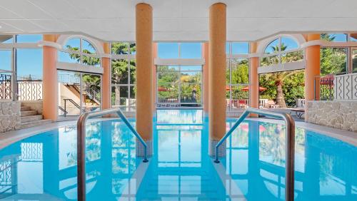 a swimming pool at a hotel with blue water and windows at Résidence les Tourelles in Sainte-Maxime