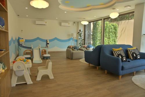 a living room with a blue couch and a play area at The Proud Karon Beach Phuket Trademark Collection By Wyndham in Karon Beach