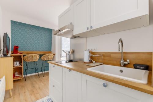 une cuisine avec des armoires blanches et un évier dans l'établissement L'estacade - charmant studio proche de la mer, à Saint-Jean-de-Monts