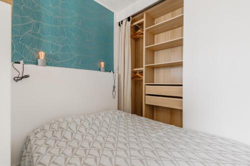 une chambre avec un lit et un mur bleu dans l'établissement L'estacade - charmant studio proche de la mer, à Saint-Jean-de-Monts