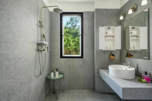 a bathroom with a sink and a shower with a window at Bay Villas Koh Phangan in Salad Beach