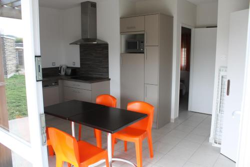 a kitchen with a black table and orange chairs at Village Vacances Passion Le Cezallier in Ardes-sur-Couze