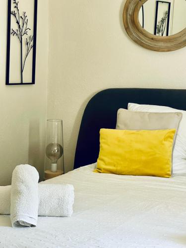 a bed with a yellow pillow and a mirror at Zen et Chic, juste à coté de la Bastide de Marie in Ménerbes