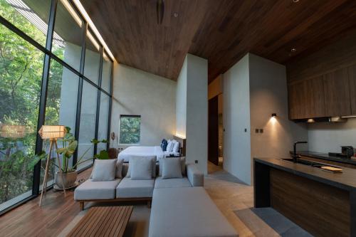 a living room with a couch and a kitchen with windows at Piece Lio Resort from Japan in El Nido