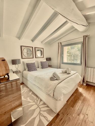 a bedroom with a large white bed and a window at Zen et Chic, juste à coté de la Bastide de Marie in Ménerbes