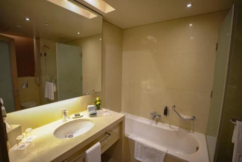 a bathroom with a sink and a tub and a mirror at Erbil Rotana in Erbil