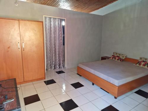 1 dormitorio con 1 cama, armario y suelo de baldosa en Bungalow chez Mouch Nosy-Be 3, en Nosy Be
