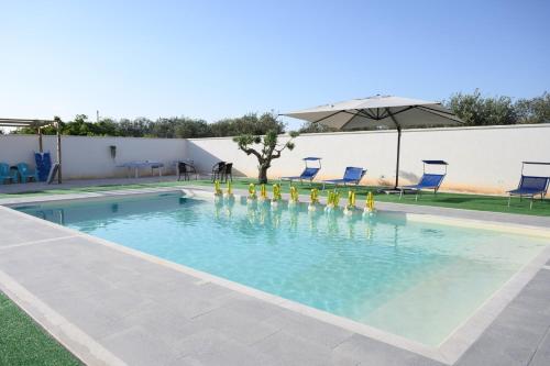 a swimming pool with chairs and an umbrella at Villa La Gardenia in Marsala