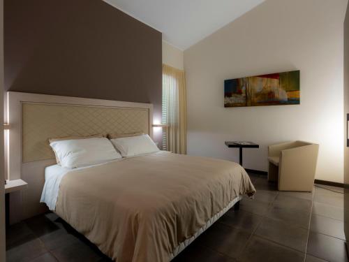 a bedroom with a large white bed and a chair at Il Castagneto Hotel in Melfi