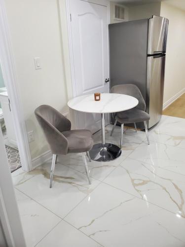a kitchen with a table and two chairs and a refrigerator at RAESABU GUEST HOUSE in Brampton