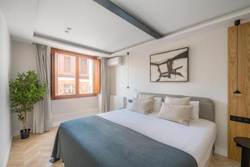 1 dormitorio con cama blanca y manta azul en Luxury flat Mayor V, en Madrid