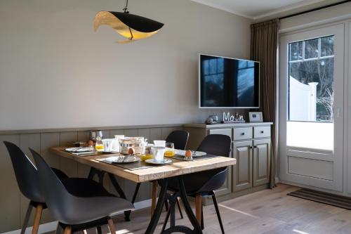 jadalnia ze stołem, krzesłami i telewizorem w obiekcie Duene@No.50 beim Strand w mieście Westerland