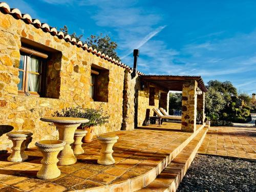 a stone house with a patio with two vases at Poolhouse with private pool 360 degrees views over pure nature in Alozaina
