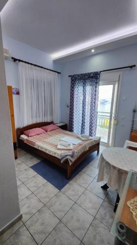 a bedroom with a bed and a large window at Paschalitsa Rooms in Prinos