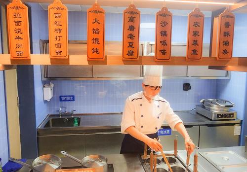 um chef de cozinha a preparar comida em Holiday Inn Express Liaocheng ETDZ by IHG em Liaocheng