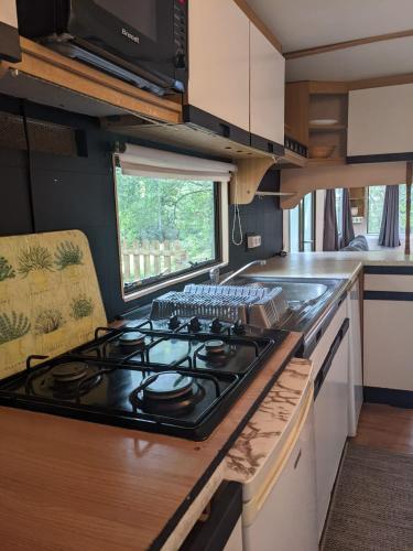 une cuisine avec une cuisinière dans une caravane dans l'établissement mobile home Norman à louer dans un charmant village, à Blangy-le-Château