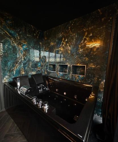 a room with a stone wall with a black tub at Eco House 1 in Prestatyn