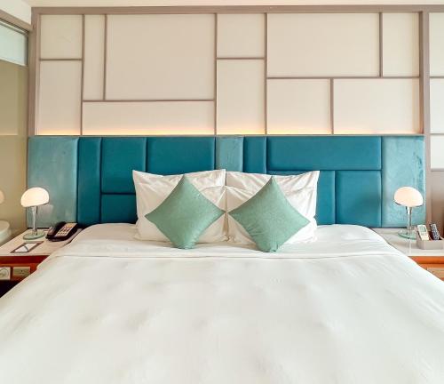 a bedroom with a large white bed with two pillows at Seaesta Nha Trang Hotel in Nha Trang