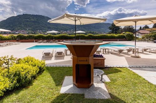 a table with an umbrella next to a swimming pool at Villa Vitali - Bellagio in Bellagio