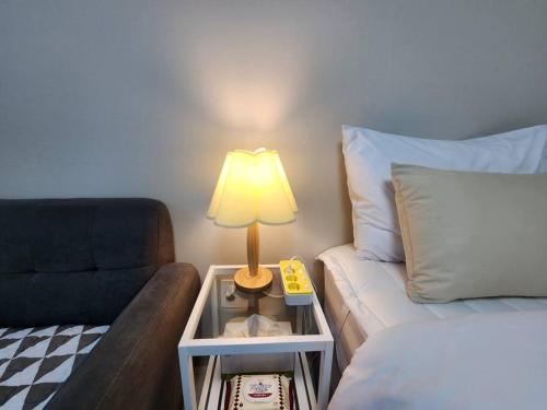 a room with a bed and a lamp next to a couch at Daon 동성로 스타비앤비 레지던스 in Daegu