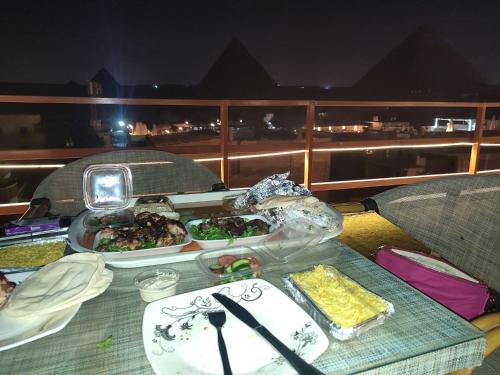a table with plates of food on top of a balcony at Narmer Pyramids View in Cairo