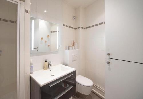 une salle de bain blanche avec un lavabo et des toilettes dans l'établissement Appartement élégant Paris centre, à Paris