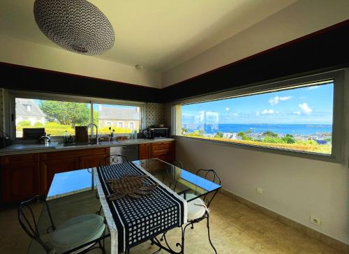 une salle à manger avec une table et deux grandes fenêtres dans l'établissement Maison KER TITOU., à Ploubazlanec