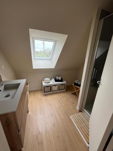 une salle de bains mansardée avec lavabo et fenêtre. dans l'établissement villa Le Sillage, à Jullouville