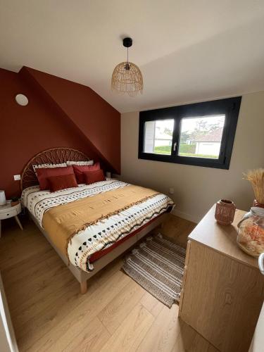 une chambre avec un grand lit avec des oreillers rouges dans l'établissement villa Le Sillage, à Jullouville