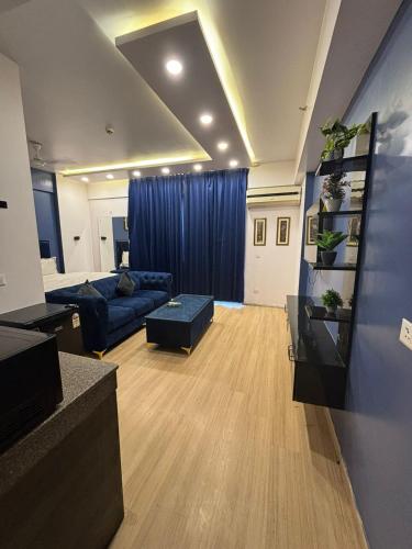 a living room with a blue couch and a blue curtain at The Royal Suites Gomti Nagar Lucknow in Lucknow