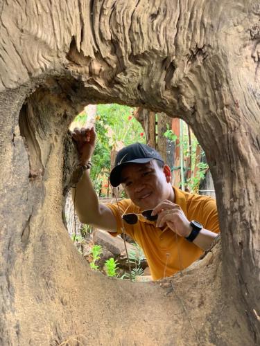a man is looking through a hole in a tree at Khu Du Lịch Sinh Thái, Nghỉ dưỡng Homestay Hoàng Ánh - Kon Xom Luh in Kon Tum