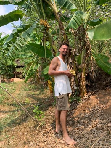 a man is standing next to a banana tree at Khu Du Lịch Sinh Thái, Nghỉ dưỡng Homestay Hoàng Ánh - Kon Xom Luh in Kon Tum