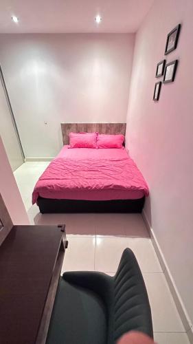 a small bedroom with a pink bed and a chair at QuiteSpace in Kluang