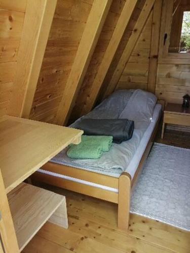a small bed in a wooden cabin with a table at Katun in Vrdnik